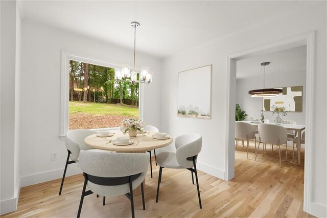 dining space with baseboards, light wood-type flooring, and a chandelier