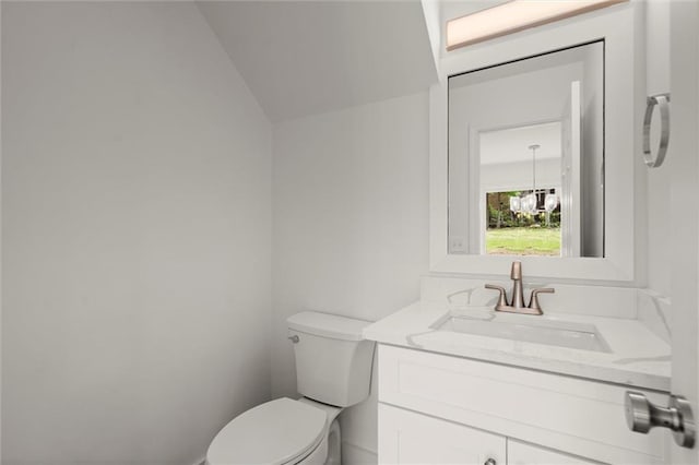 half bath with toilet, lofted ceiling, and vanity