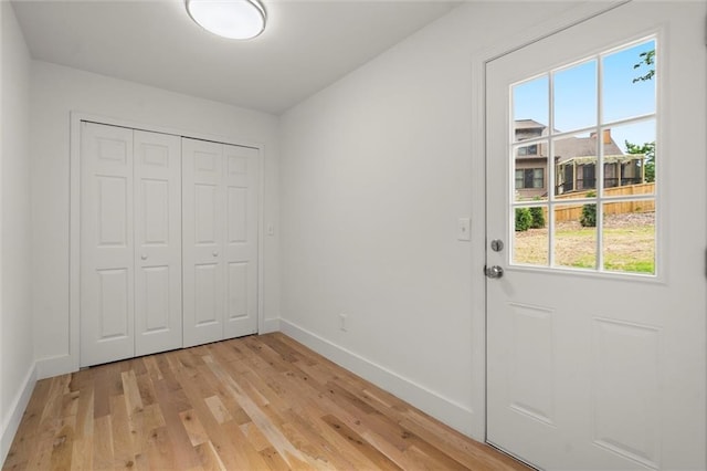 doorway to outside featuring light wood-style floors, baseboards, and a wealth of natural light