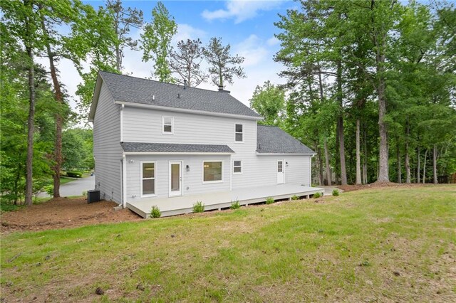 rear view of property featuring a shingled roof, a yard, and central AC unit