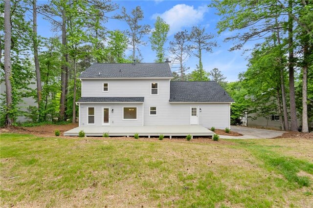 back of property with roof with shingles, a yard, and a deck
