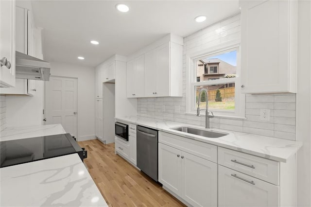 kitchen with white cabinetry, tasteful backsplash, a sink, light wood-style flooring, and black appliances