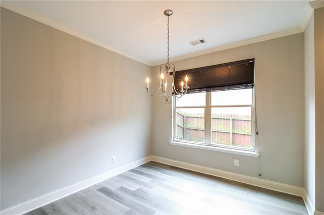 spare room featuring ornamental molding, a chandelier, and hardwood / wood-style floors