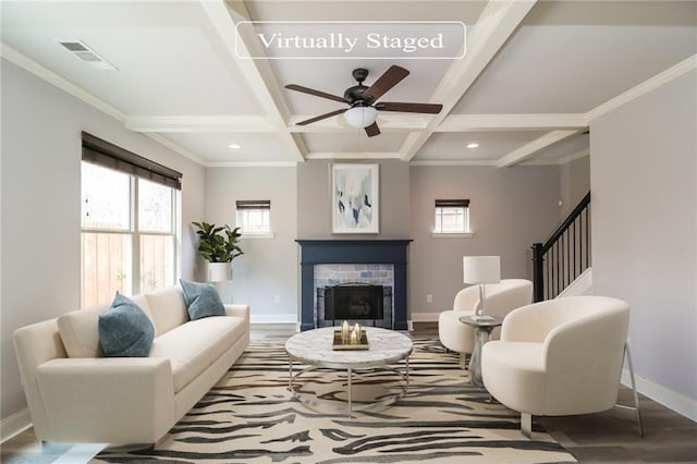 living room with coffered ceiling, hardwood / wood-style floors, a fireplace, ceiling fan, and beamed ceiling