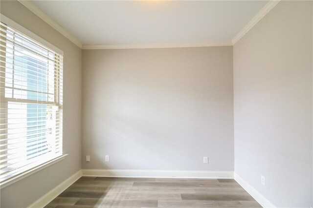 empty room featuring hardwood / wood-style flooring, ornamental molding, and plenty of natural light