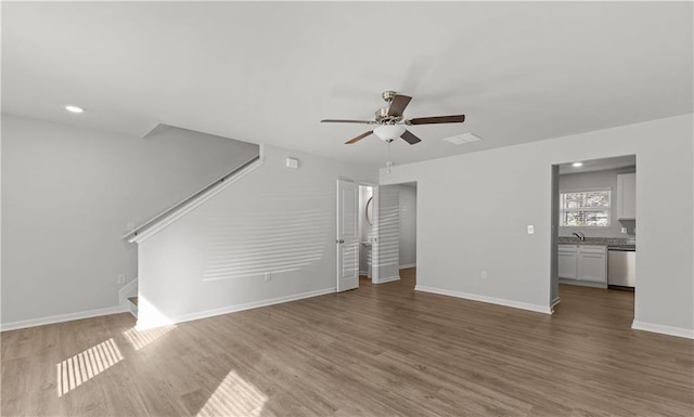 unfurnished living room with sink, ceiling fan, and light hardwood / wood-style flooring