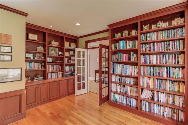 living area with light wood-style floors, crown molding, recessed lighting, french doors, and bookshelves
