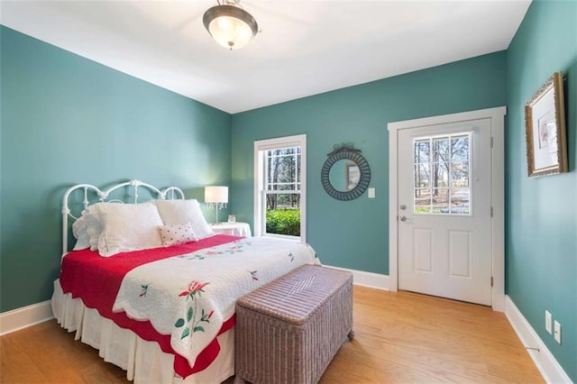 bedroom with multiple windows, wood finished floors, and baseboards