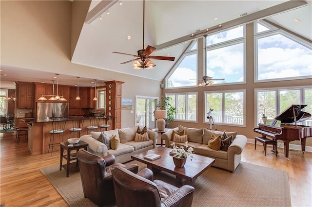 living room featuring high vaulted ceiling, light wood finished floors, beamed ceiling, and ceiling fan