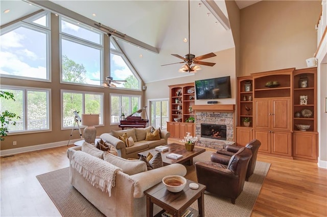 living room with high vaulted ceiling, a stone fireplace, a healthy amount of sunlight, and ceiling fan