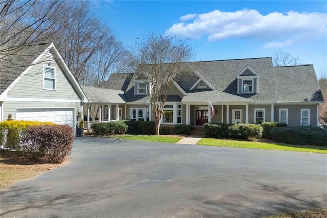 view of front of home with a garage, roof with shingles, and driveway