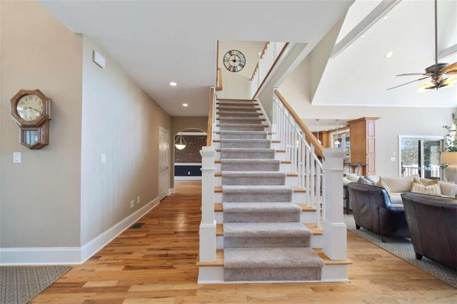 stairway with a ceiling fan, wood finished floors, recessed lighting, arched walkways, and baseboards