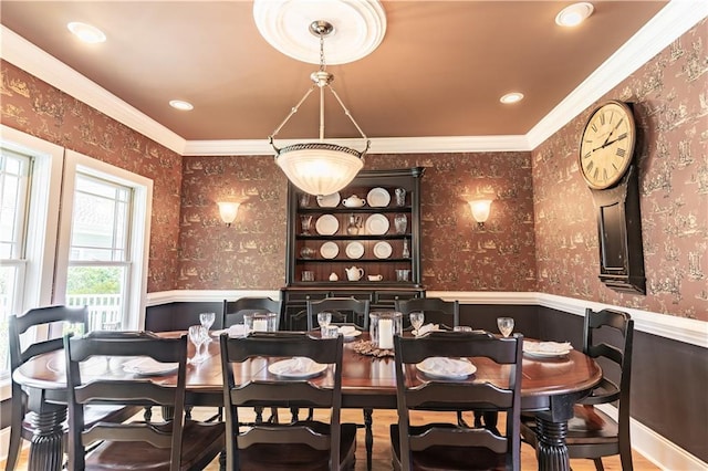dining room with crown molding, a wainscoted wall, and wallpapered walls