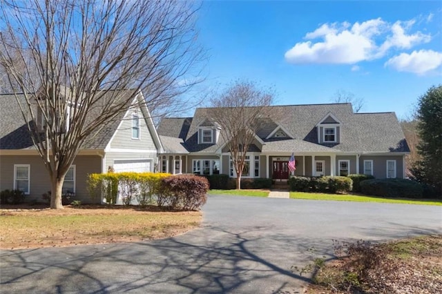 new england style home featuring aphalt driveway, a front yard, and an attached garage