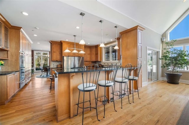 kitchen featuring a breakfast bar area, brown cabinetry, light wood-style flooring, glass insert cabinets, and appliances with stainless steel finishes