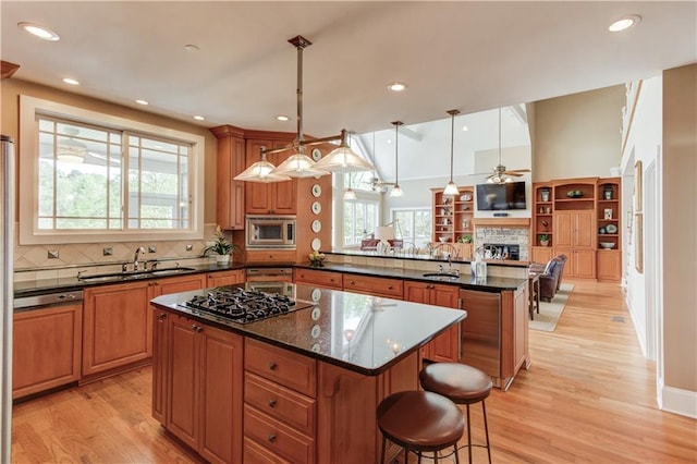 kitchen with a peninsula, gas stovetop, a kitchen island, stainless steel microwave, and a sink