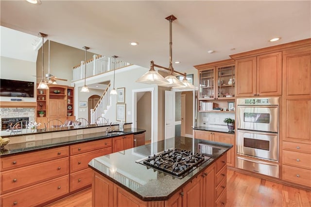 kitchen featuring light wood-style flooring, open floor plan, a warming drawer, and appliances with stainless steel finishes