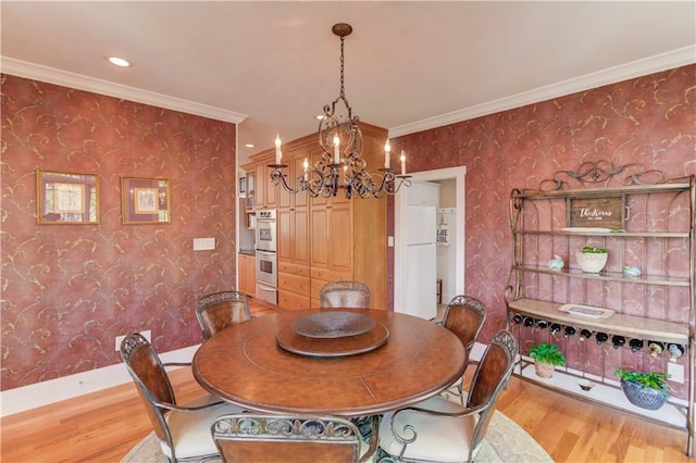 dining area featuring wallpapered walls, wood finished floors, a notable chandelier, and baseboards