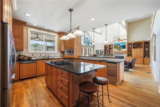 1126 Shoreline Dr, Jefferson, GA 30549 - kitchen featuring stainless steel appliances, a peninsula, brown cabinetry, a sink, and a kitchen island