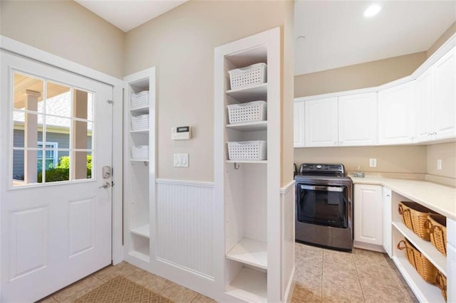 interior space with light tile patterned floors, a wainscoted wall, and washer / dryer