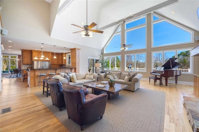 living room featuring baseboards, visible vents, high vaulted ceiling, recessed lighting, and light wood-style floors