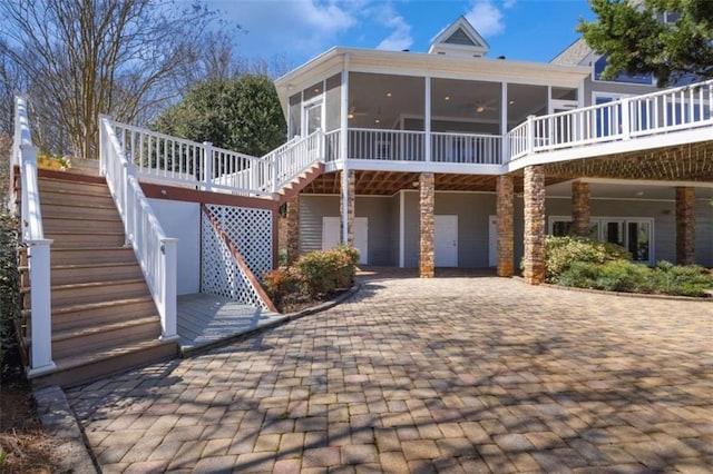 back of house featuring stairway, a sunroom, and driveway