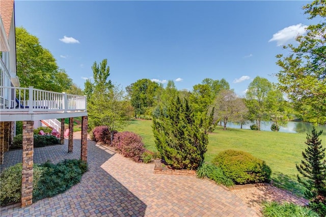 view of yard featuring a patio, a deck with water view, and stairs