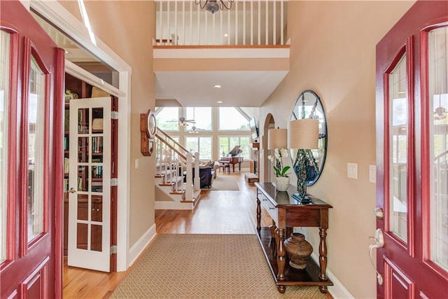 entrance foyer featuring wood finished floors, a towering ceiling, baseboards, and stairway