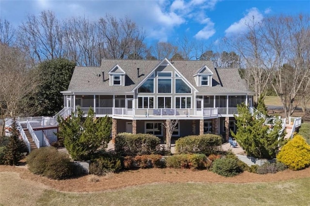 back of property featuring stairs, a sunroom, and a lawn