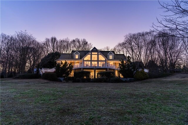 back of property at dusk with a yard and a wooden deck
