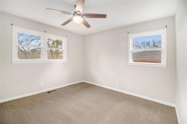 carpeted spare room featuring ceiling fan