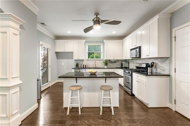 kitchen featuring decorative columns, appliances with stainless steel finishes, white cabinets, and plenty of natural light