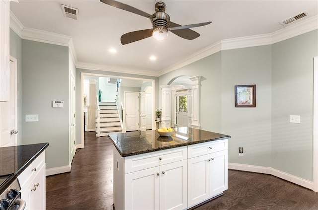 kitchen featuring white cabinetry, dark stone counters, dark hardwood / wood-style floors, crown molding, and a center island