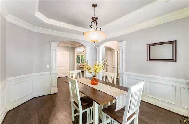 dining area with crown molding, dark hardwood / wood-style floors, a tray ceiling, and decorative columns