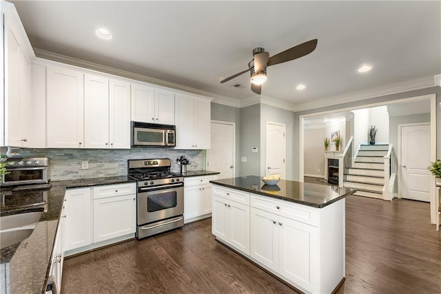 kitchen with dark wood-type flooring, dark stone countertops, appliances with stainless steel finishes, and white cabinets