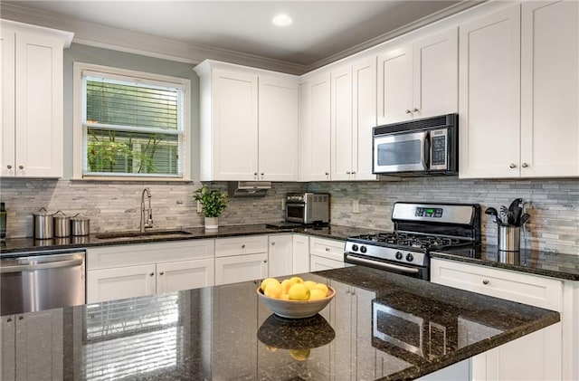 kitchen with sink, stainless steel appliances, white cabinets, dark stone countertops, and decorative backsplash