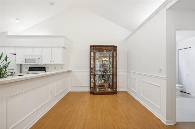 kitchen featuring white cabinetry, light hardwood / wood-style flooring, black range oven, and vaulted ceiling