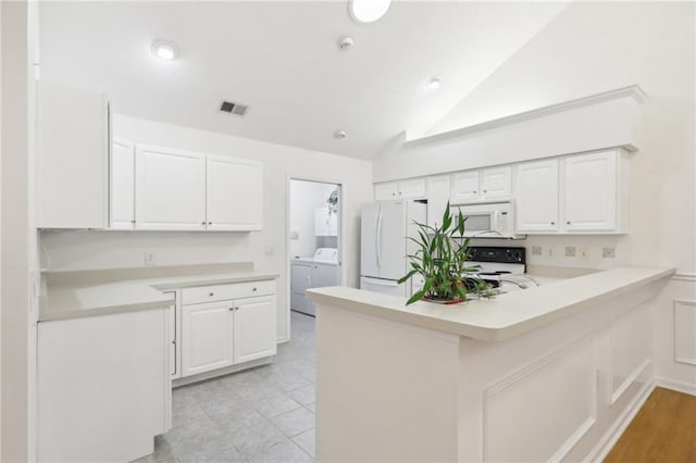 kitchen featuring washer and dryer, white cabinetry, and white appliances