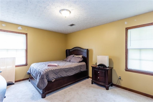 carpeted bedroom with baseboards, a textured ceiling, and visible vents