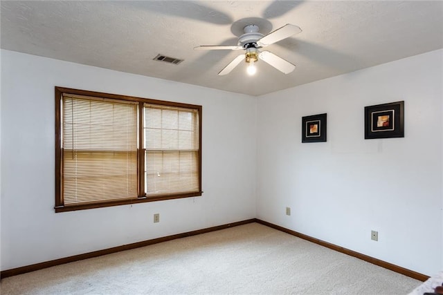 unfurnished room featuring baseboards, ceiling fan, light colored carpet, and visible vents