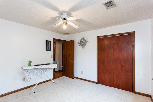 bedroom with light colored carpet, a ceiling fan, baseboards, visible vents, and a closet