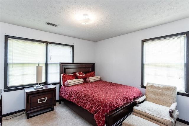 bedroom featuring visible vents, a textured ceiling, and light carpet