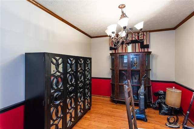 interior space featuring crown molding, a textured ceiling, wood finished floors, and a chandelier
