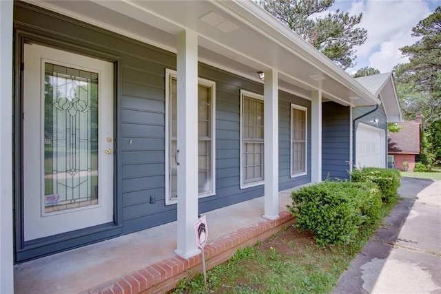 view of property exterior featuring a porch, an attached garage, and driveway