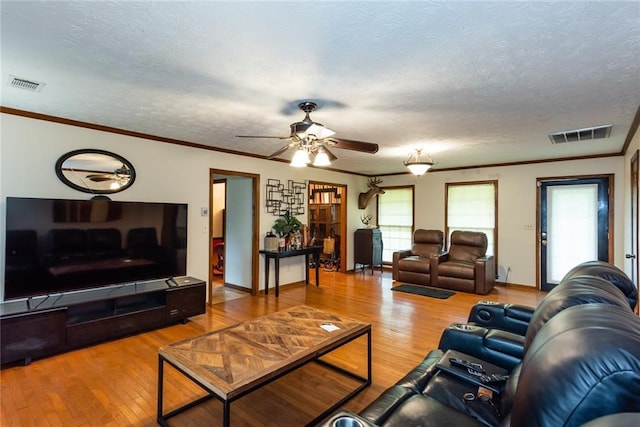 living area with visible vents, a ceiling fan, wood-type flooring, and a textured ceiling