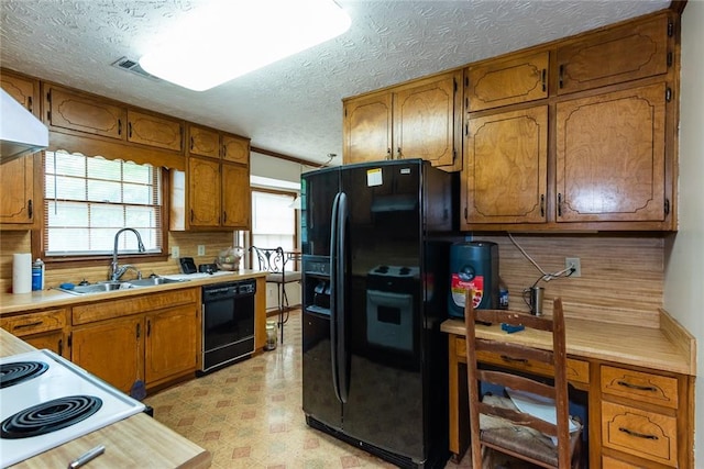 kitchen with a sink, light floors, brown cabinets, and black appliances
