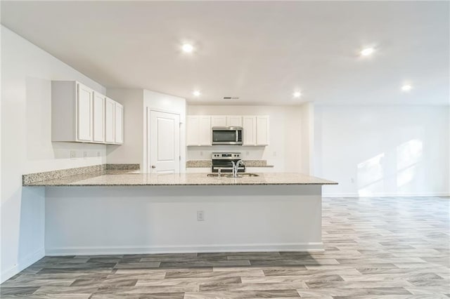 kitchen featuring stainless steel appliances, white cabinetry, light hardwood / wood-style flooring, and kitchen peninsula