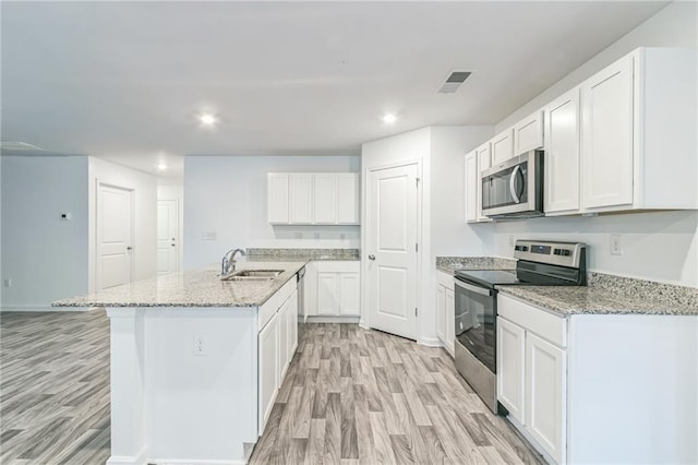 kitchen featuring a center island with sink, white cabinets, light hardwood / wood-style flooring, sink, and appliances with stainless steel finishes