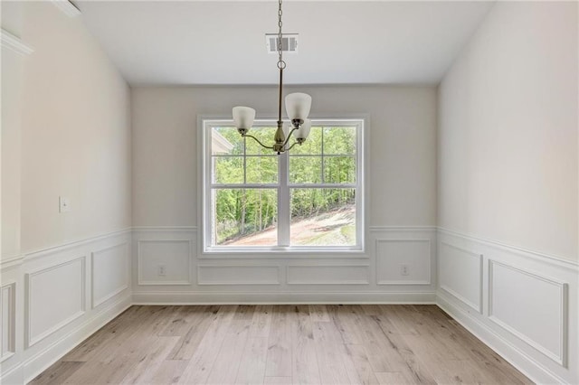 unfurnished dining area featuring a chandelier and light wood-type flooring