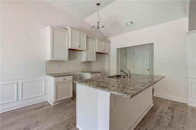 kitchen with white cabinetry, an island with sink, decorative light fixtures, and sink